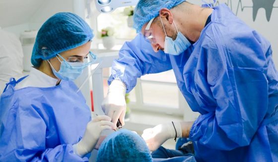 Лучшие-стоматологи-Молдова Стоматолог-хирург ассистируемый медсестрой вставляет импланты в стоматологической клинике в Кишиневе